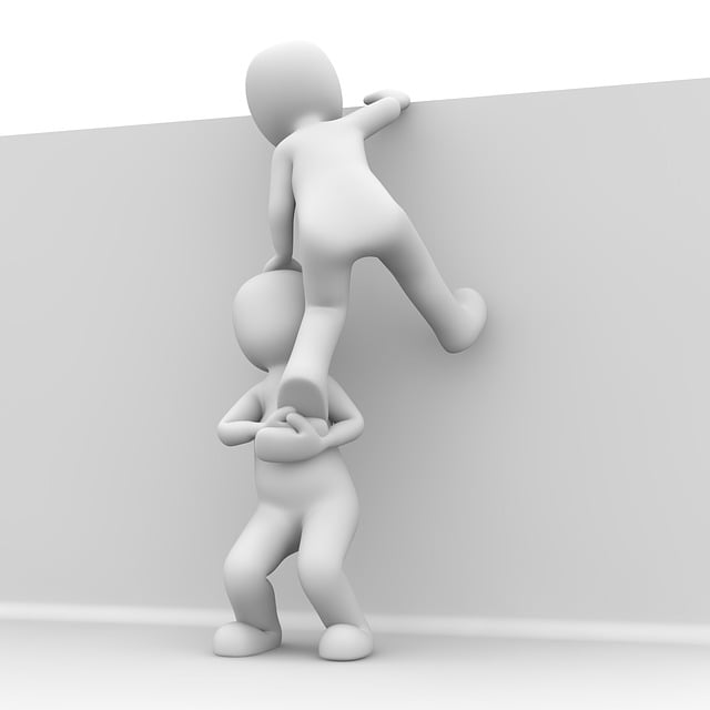 Zwei Figuren; eine hilft der anderen über eine Mauer.